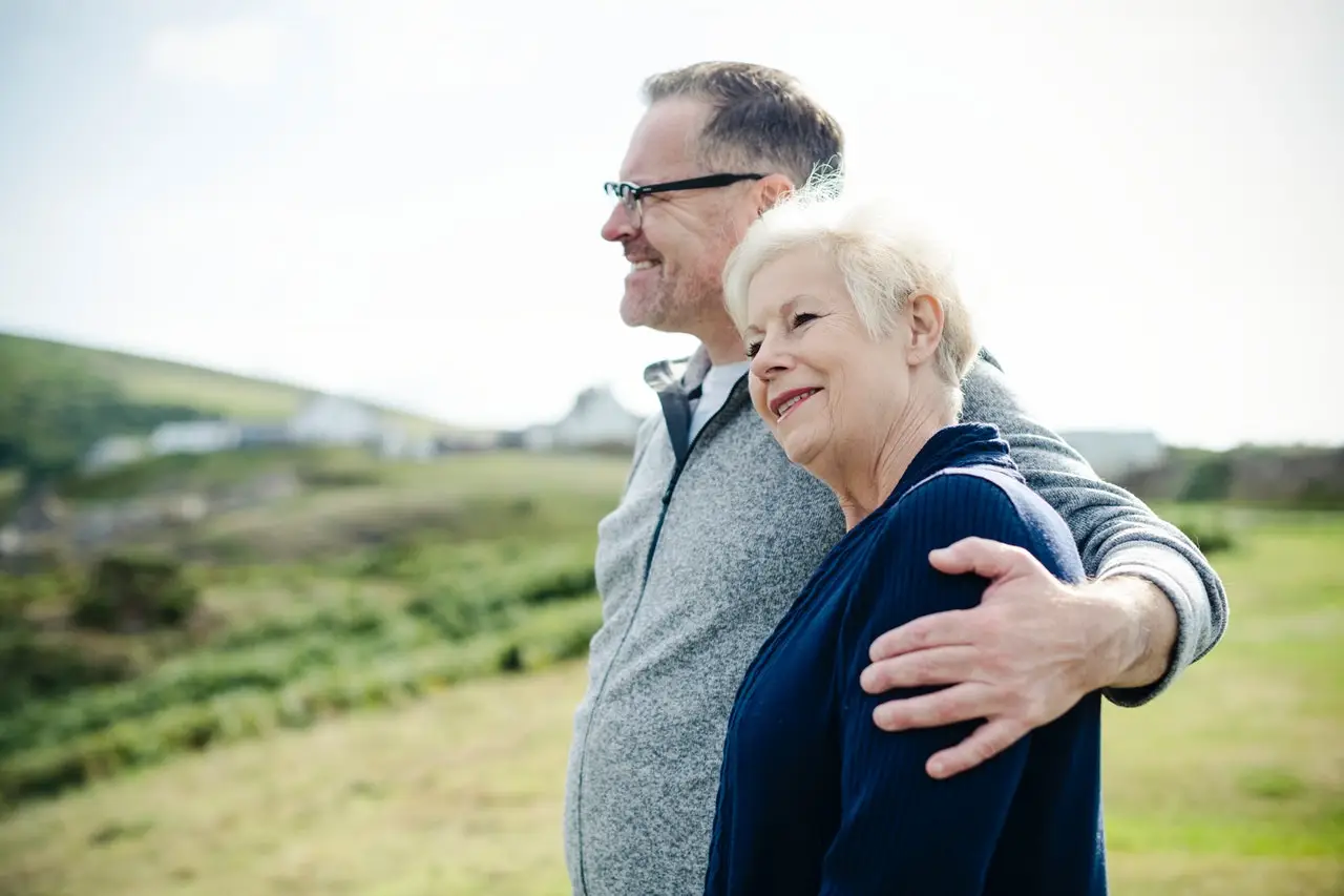 older couple smiling together in open field