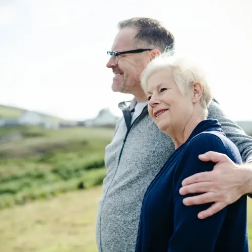 older couple smiling together in open field